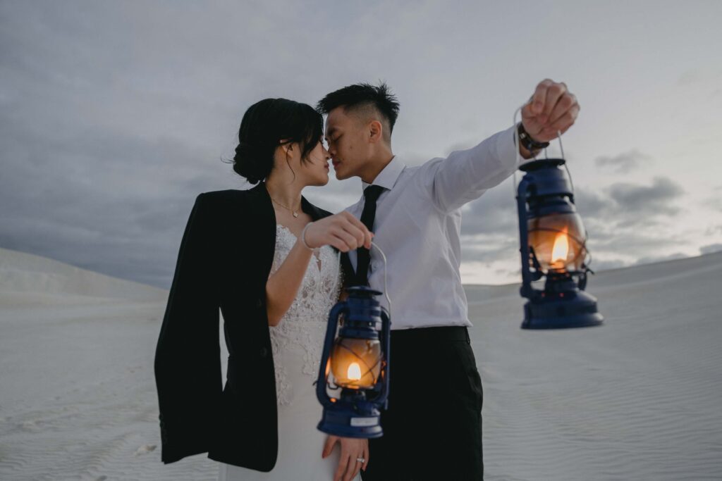 Couple kissing at Lancelin Sand Dunes holding lanterns—an ethereal and unique Western Australia pre-wedding photo location.