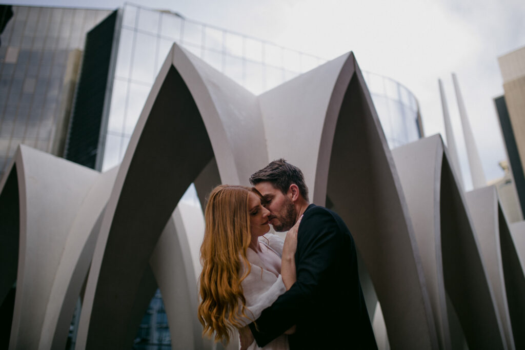 Couple embracing in front of sculptural arches during a Perth city pre-wedding shoot.