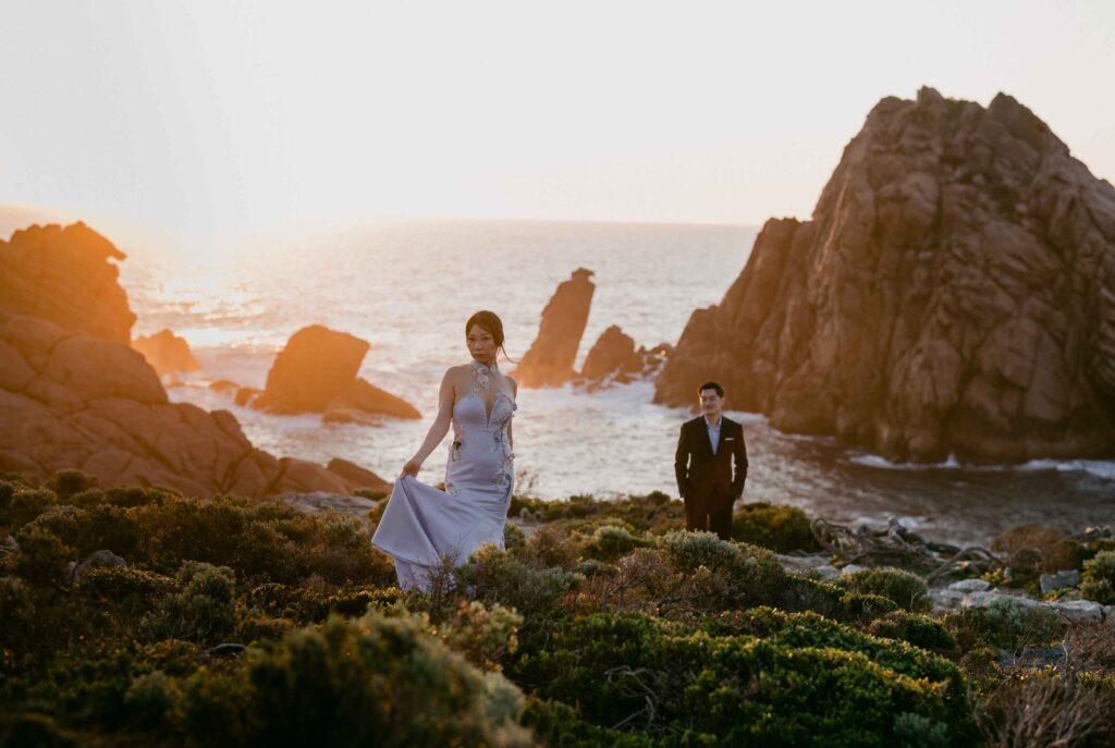 Bride walking at sunset with groom behind her at Sugarloaf Rock — a dramatic and adventurous pre-wedding location in Western Australia.