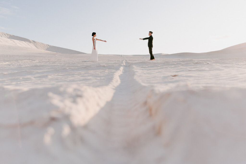 Joey and Davis reaching towards each other across the white Lancelin Sand Dunes