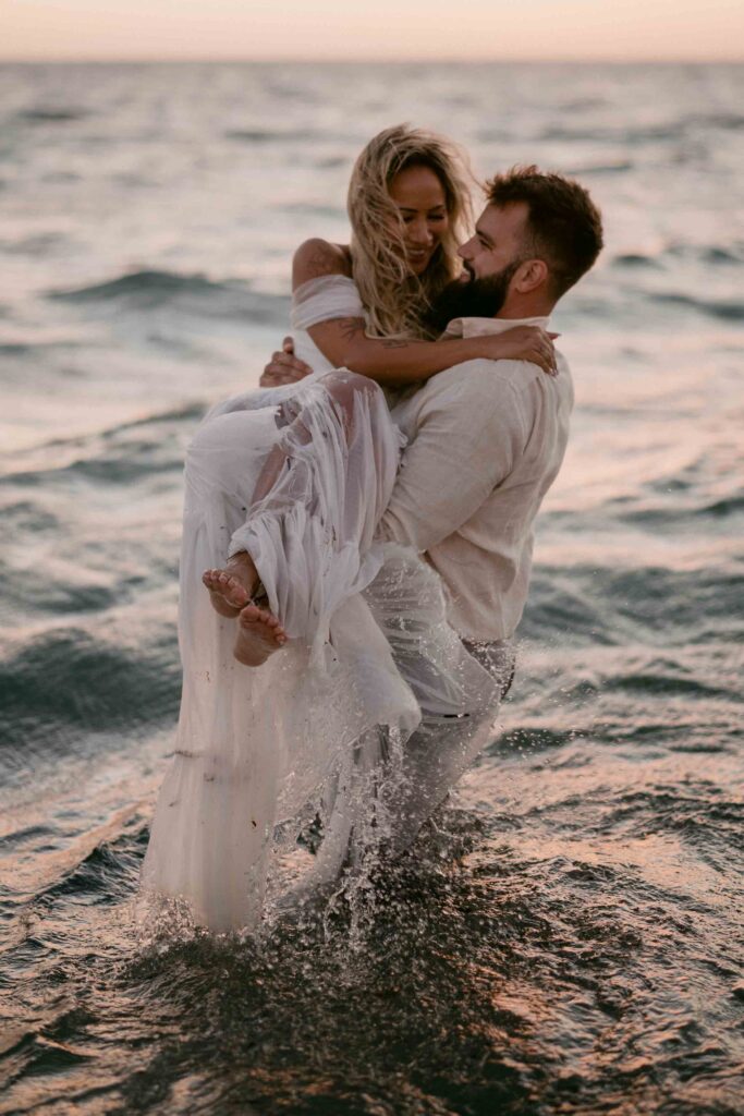 Having a celebratory ocean dip as husband and wife after their elopement with moments by naz