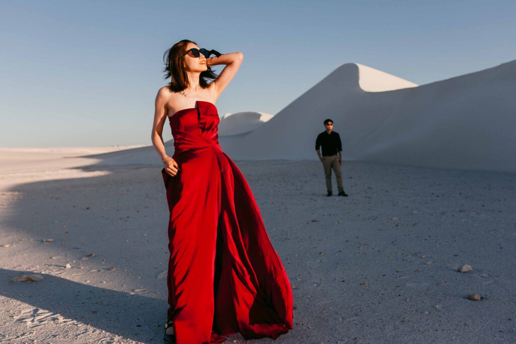 girl in red dress looking at the sun from the lancelin sand dunes during their pre-wedding photography session in Perth