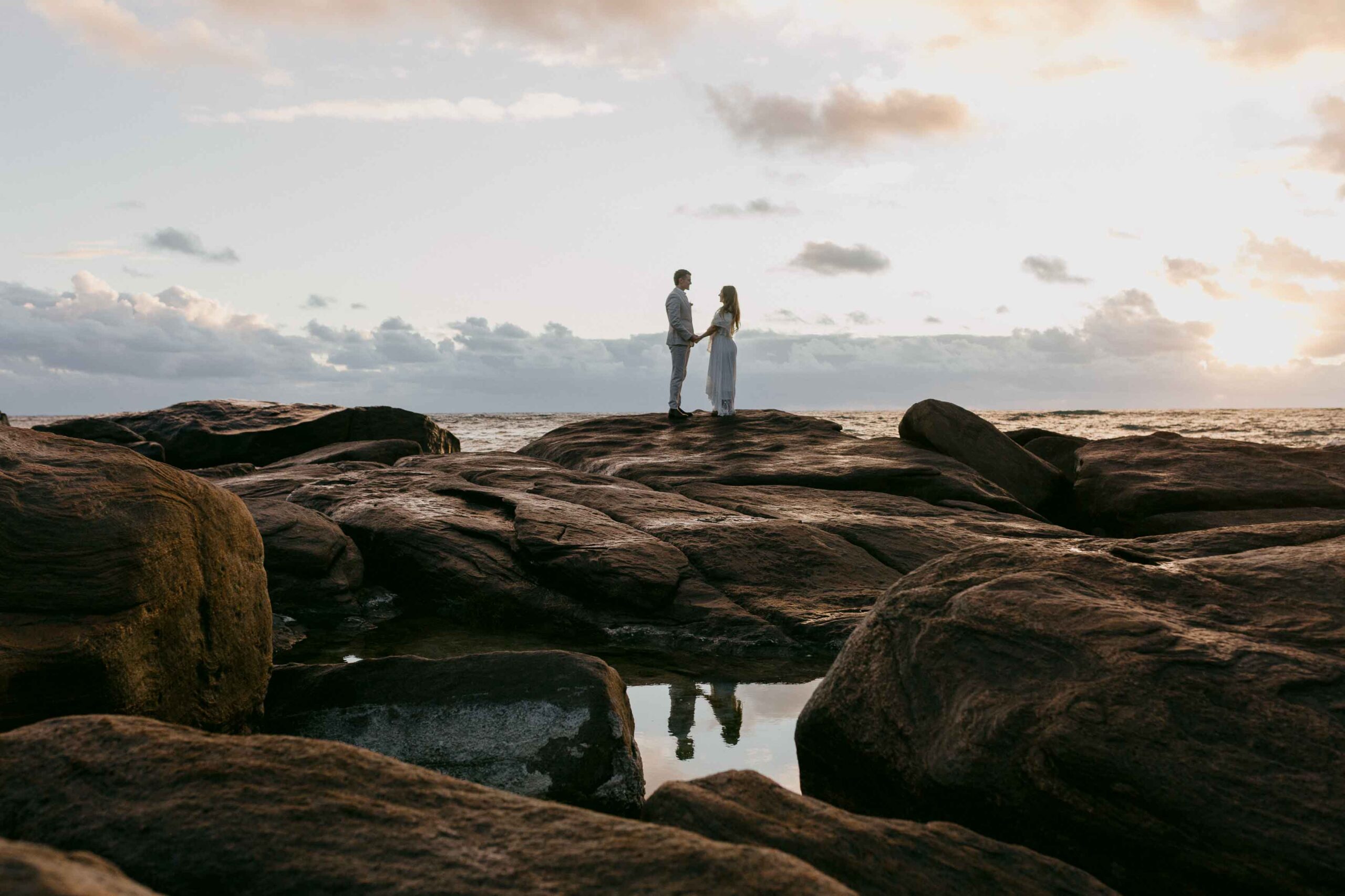 couple holding hands on the rocks of contos on the boranup coas for the destination pre-wedding shoot in perth
