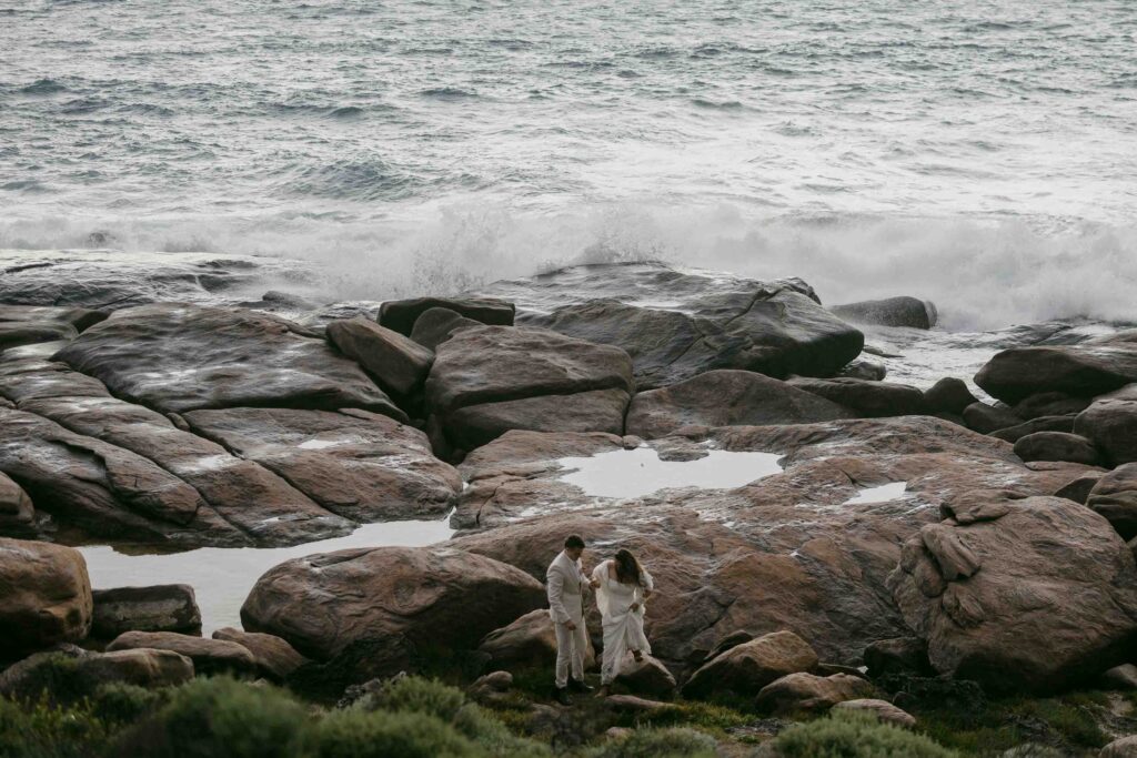 couple walking away from the coastal rocks in conto for the elopeemnt session in perth margaret river