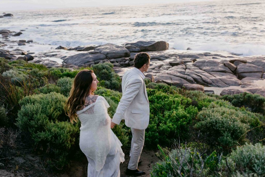 walking away together to capture sunset on the coast after the elopement
