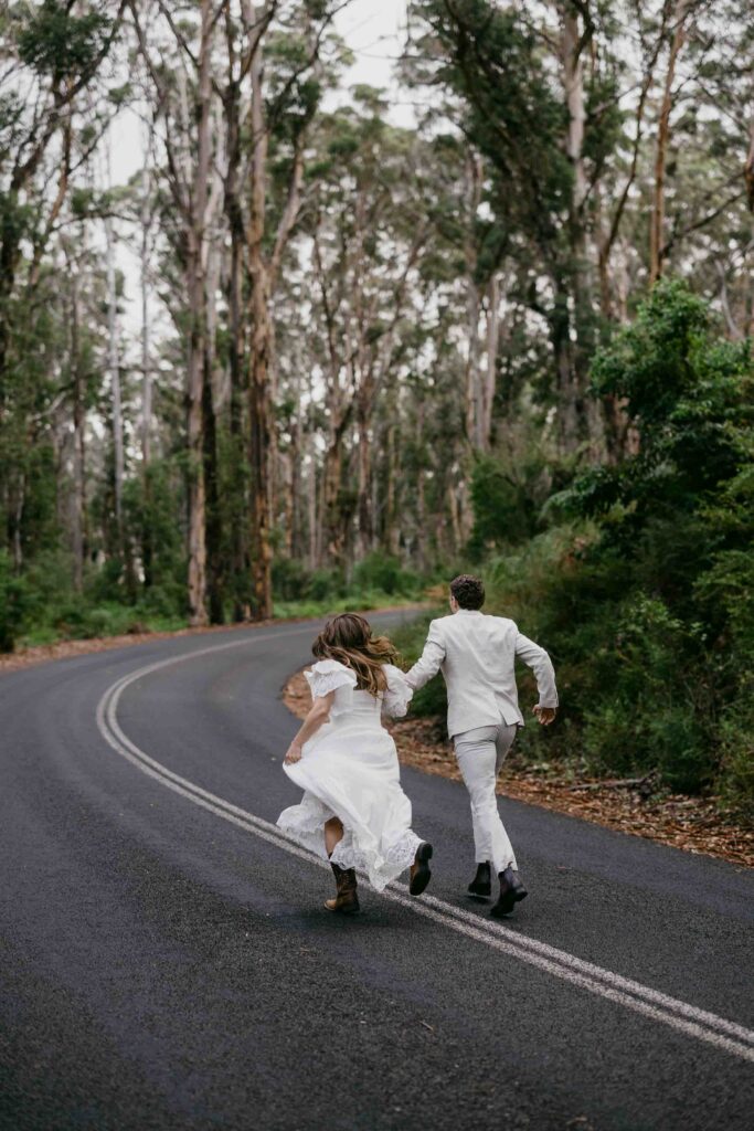 couple running up caves road in boranup forrest for the elopement shoot in margaret river