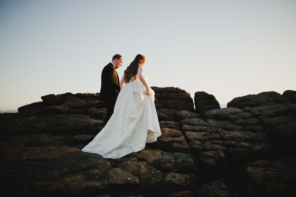 Couple walking on the rocks of prevally beach to capture the sunset for their pre-wedding shoot
