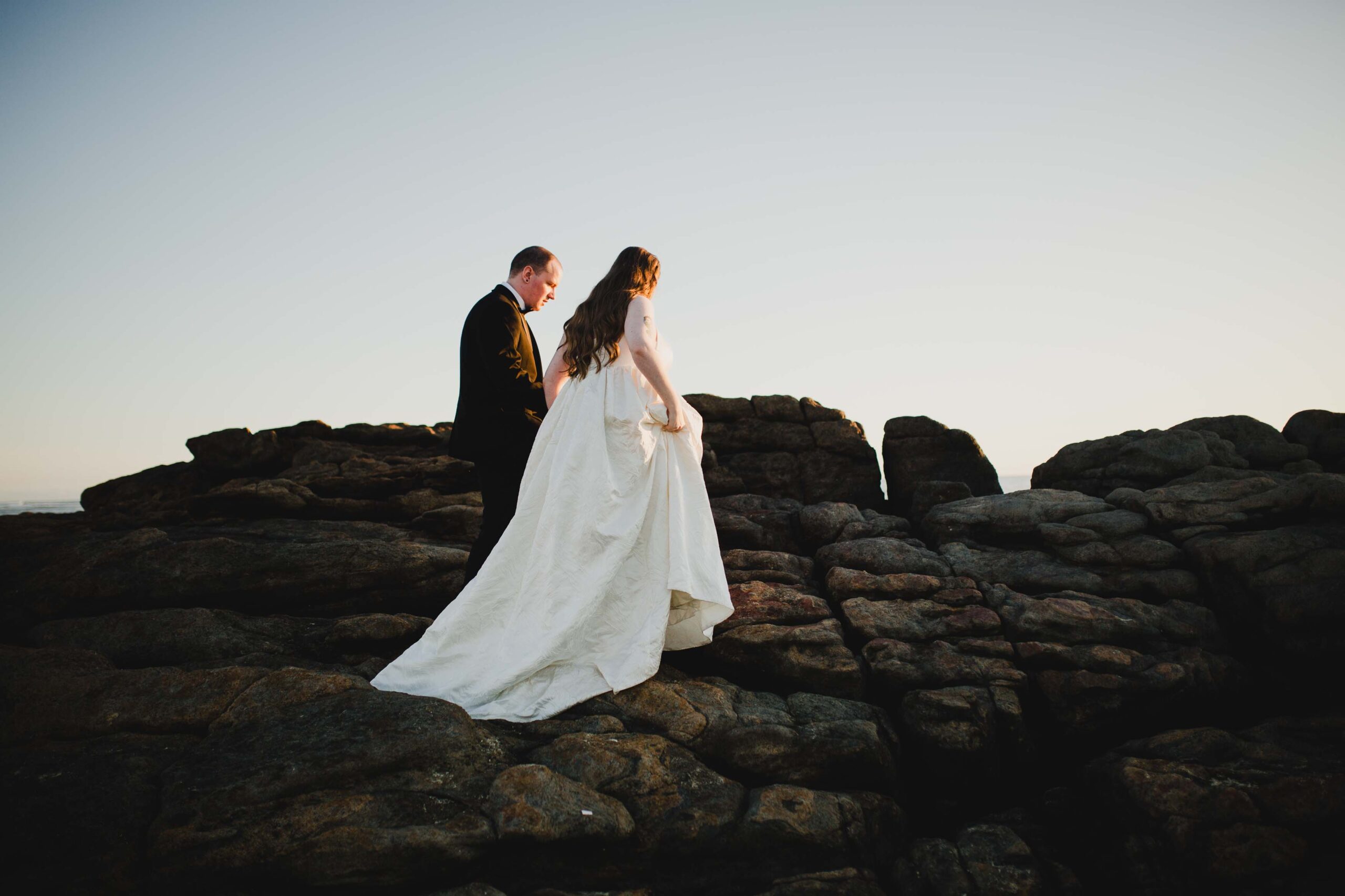Couple walking on the rocks of prevally beach to capture the sunset for their pre-wedding shoot