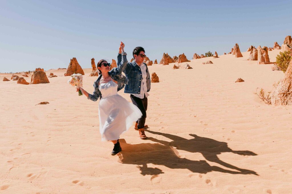 Rachel holding her bridal bouquet beside Marco at the Pinnacles Desert in Western Australia