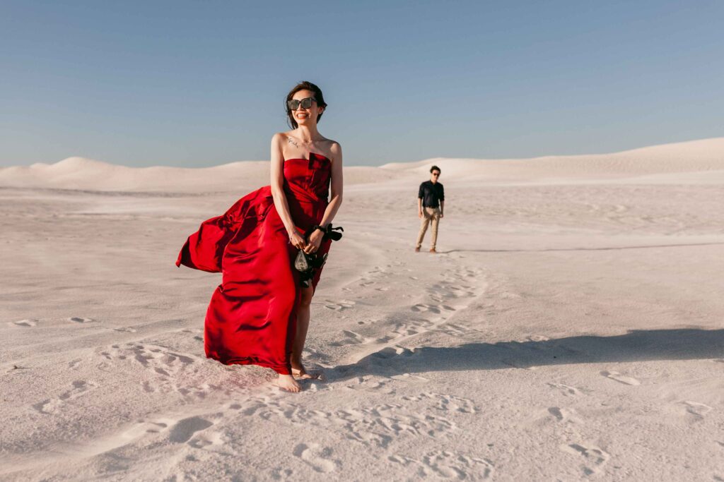 Windswept editorial pre-wedding portrait of Rachel in a red gown at the Lancelin Sand Dunes