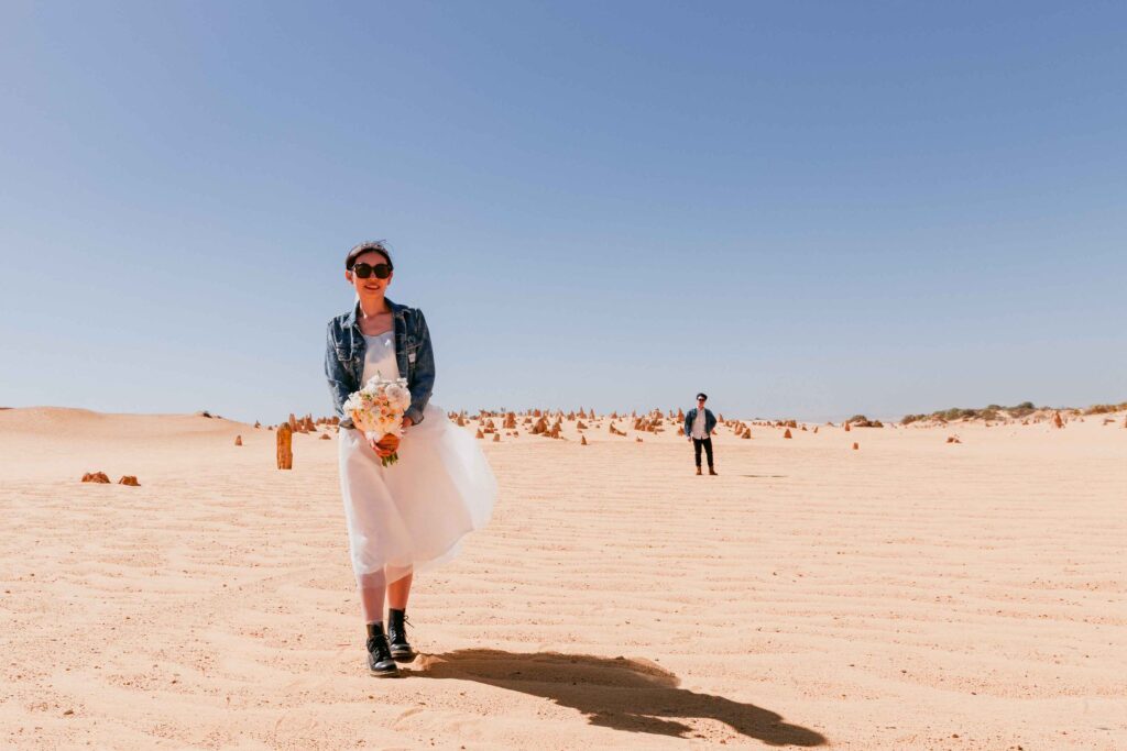 Rachel holding her bridal bouquet beside Marco at the Pinnacles Desert in Western Australia