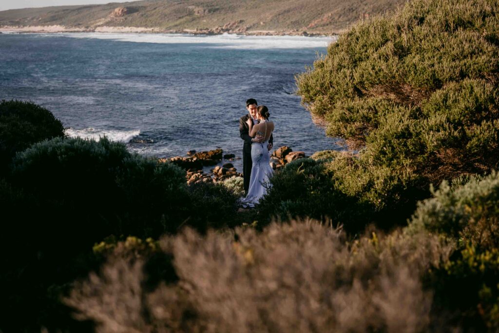 wide shot couple arriving to sugarloaf rock with beach in the backgroud