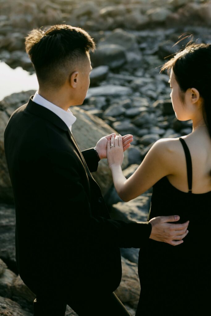 Joey and Davis holding hands during a playful moment along the rocky coastline
