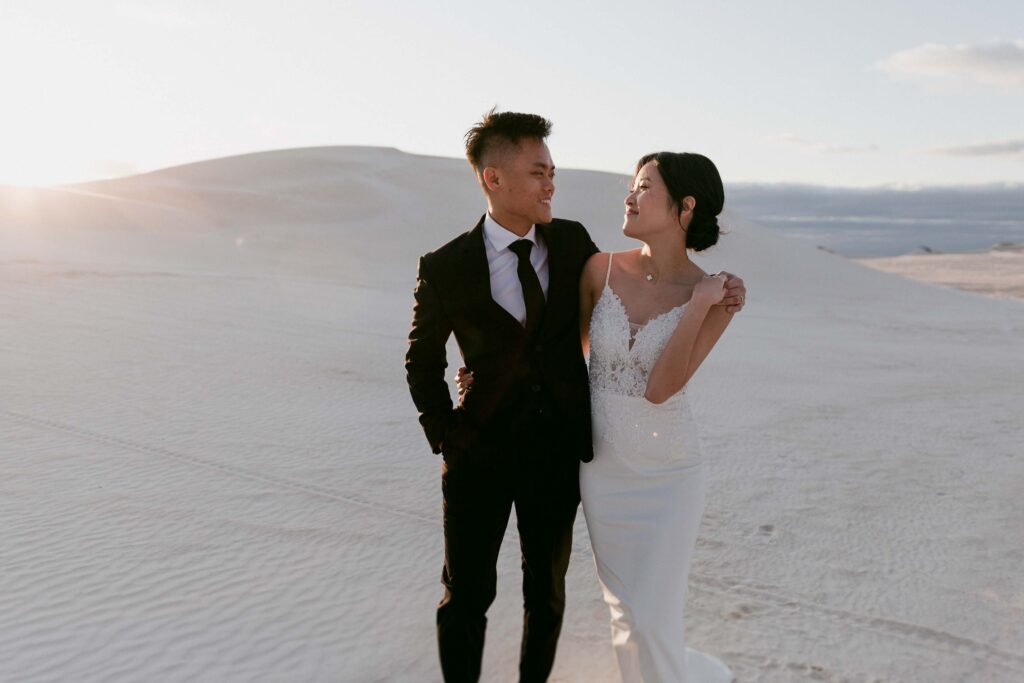 Joey and Davis walking together in formal wedding attire at Lancelin Sand Dunes