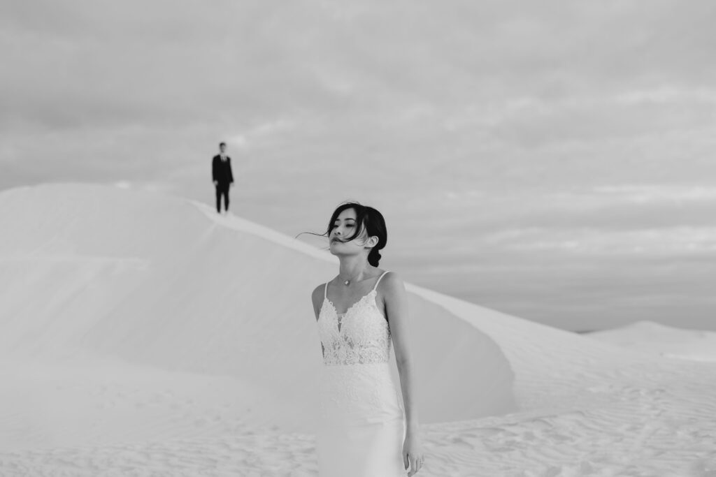 Black and white portrait of Joey and Davis separated by the rolling Lancelin dunes