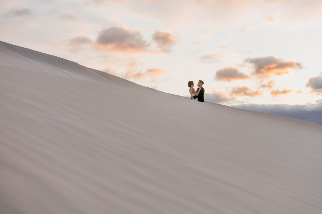 Joey and Davis silhouetted against the sunset sky from behind a Lancelin dune
