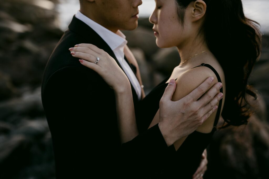 Close portrait of Joey and Davis embracing against the rocky coastal landscape