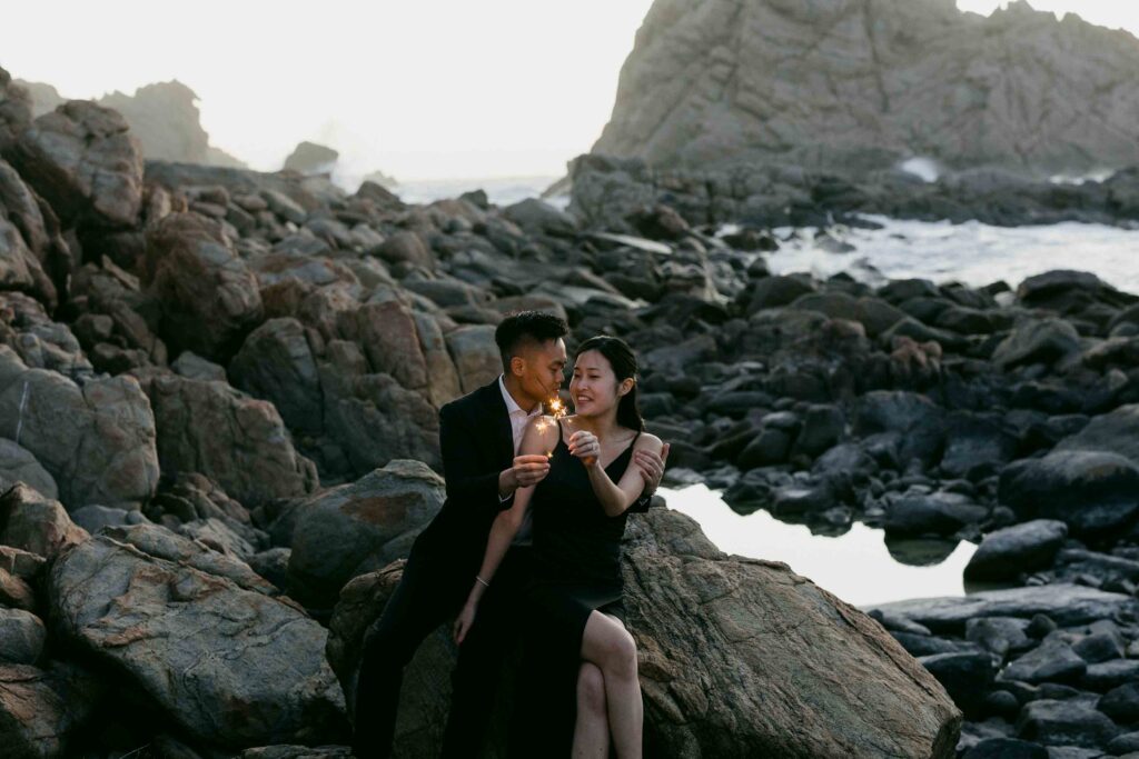 Joey and Davis sitting together with sparklers among the rocks near Sugarloaf Rock