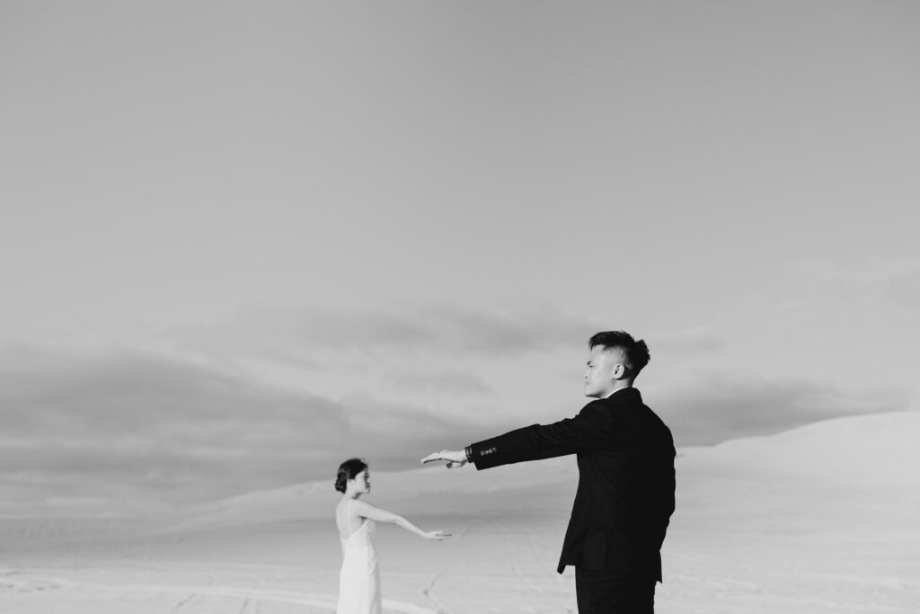 Black and white portrait of Davis reaching towards Joey among the Lancelin dunes