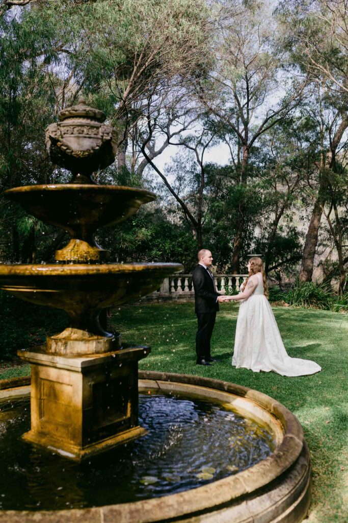 Bride and groom holding hands beyon the water fountain at La Foret Margaret River