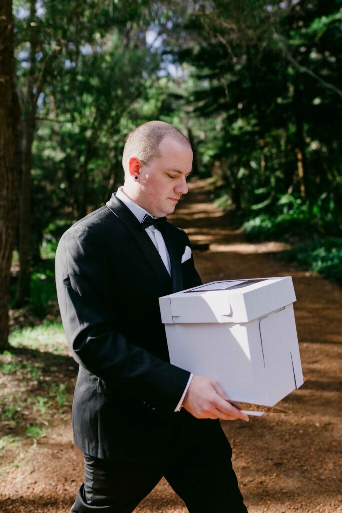 Groom holding cake box walking to get cut
