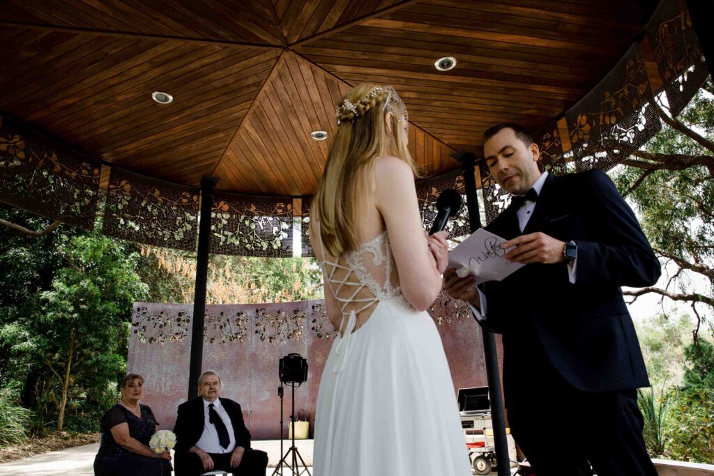 groom reading vows to wife infront of their guests uner marlee pavillion for their micro wedding in Perth Kings Park 