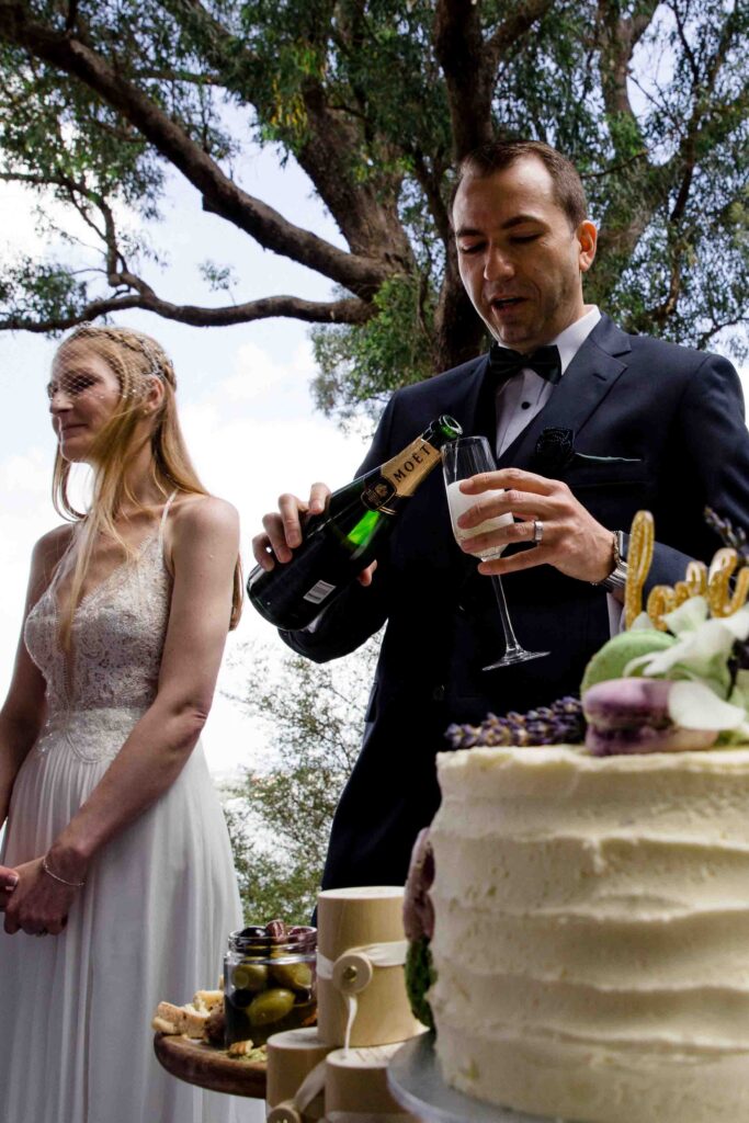 Groom pouring a drink with cake in the foreground after their micro-wedding in Kings Park 
