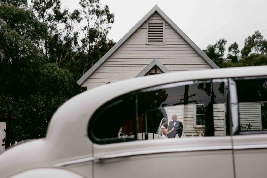 portrait of couple through the windows of la belle wedding cars