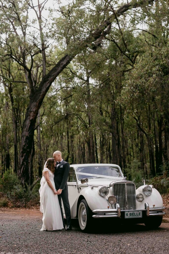 couple with belle wedding cars jaguar in the forrest