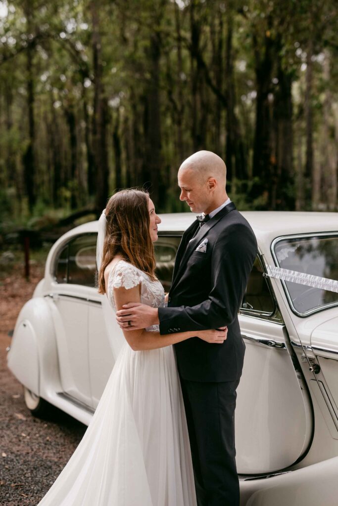 couple with belle wedding cars jaguar in the forrest