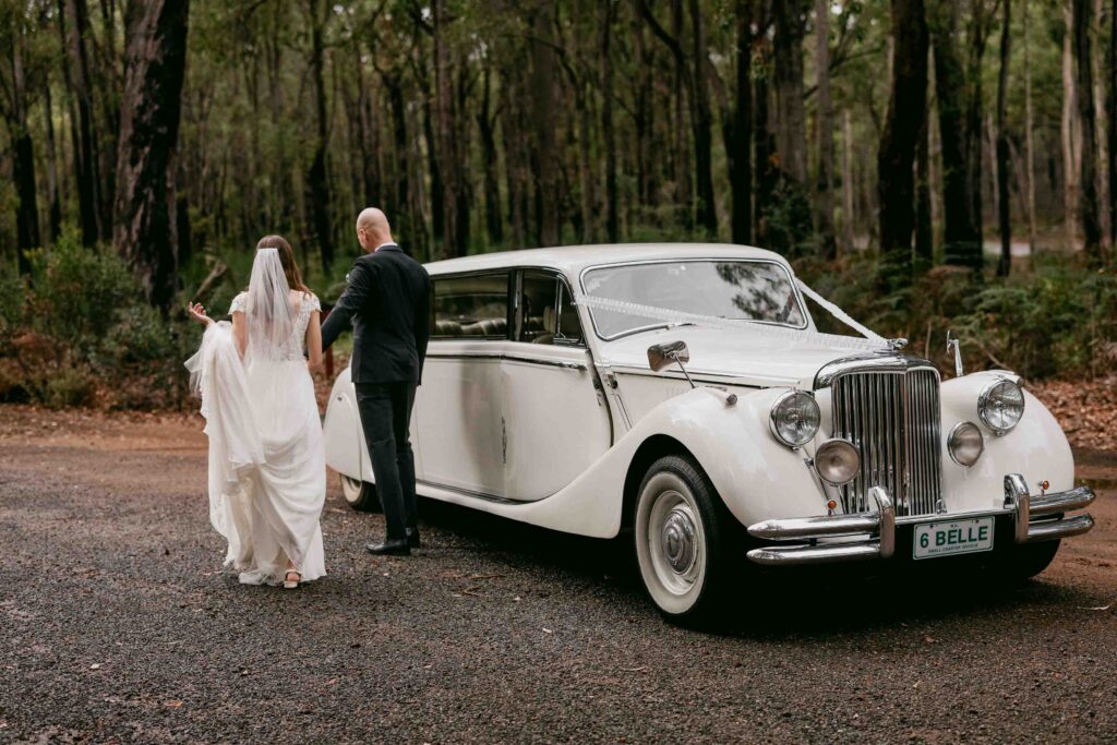 couple with belle wedding cars jaguar in the forrest