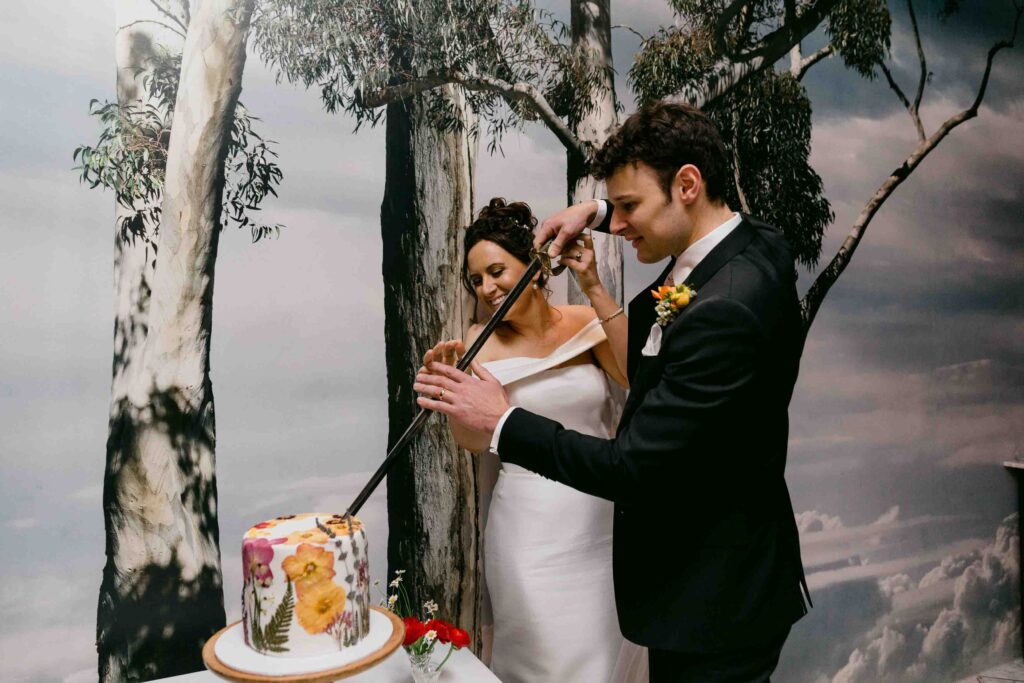 Newlyweds cutting their wedding cake with a family sword at Wildflower