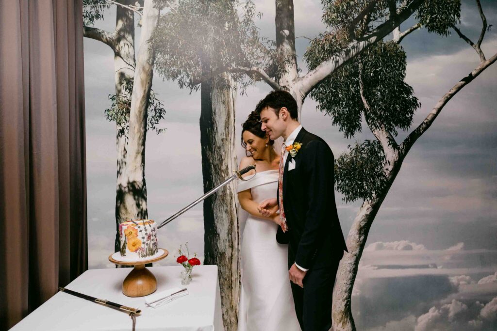 Newlyweds cutting their wedding cake with a family sword at Wildflower